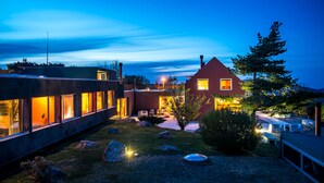 A modern house with large windows, a well-maintained garden, and a visible deck area. - Casa das Penhas Douradas - Burel Expedition Hotel (Manteigas)