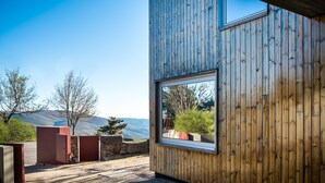 A modern building with a wooden exterior and a large window. - Casa das Penhas Douradas - Burel Expedition Hotel (Manteigas)