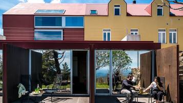 A modern house with a glass extension, outdoor seating, and a view of the landscape.