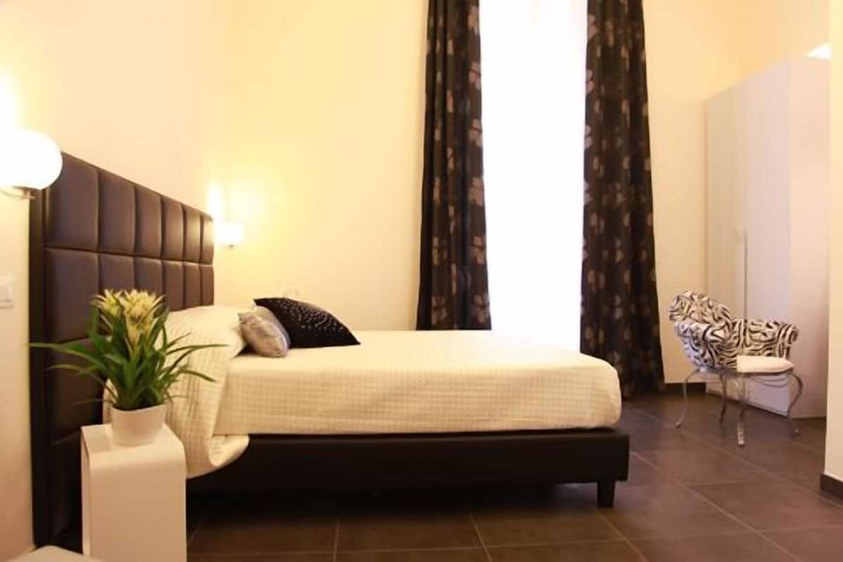 A bedroom with a large bed, a nightstand, a potted plant, and a tiger statue.
