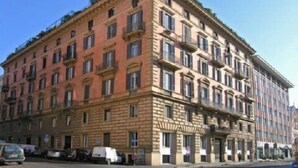 Un edificio de varios pisos con estilo arquitectónico clásico, que presenta una fachada simétrica con ventanas uniformemente distribuidas y detalles decorativos.