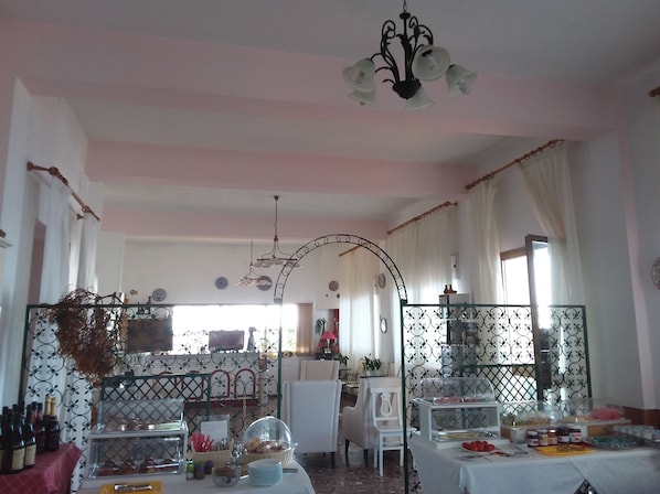 A dining area with tables, chairs, a chandelier, and a buffet. - Orpheus (Giardini Naxos)