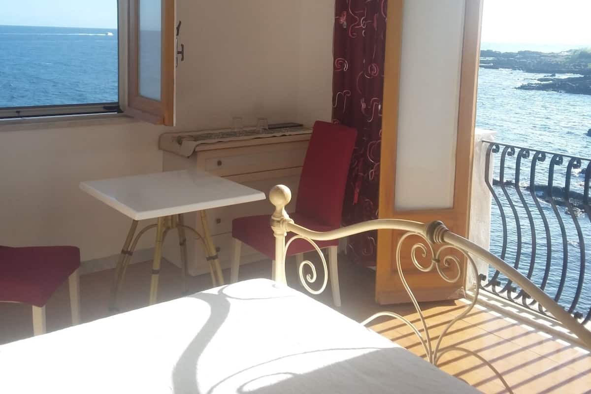 Ein Balkon mit einem Bett, einem Tisch und einem Stuhl.