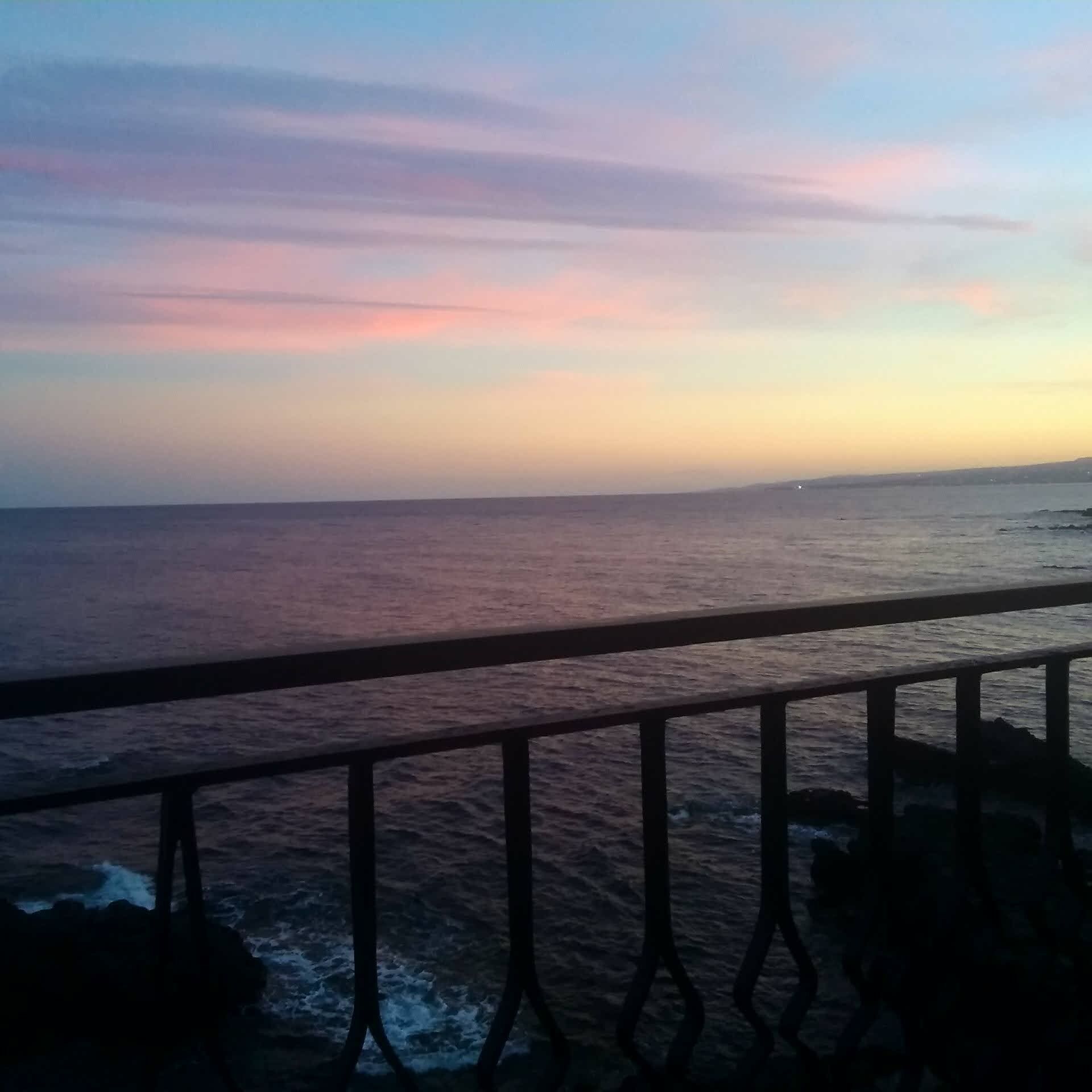 A coastal view with a railing in the foreground.