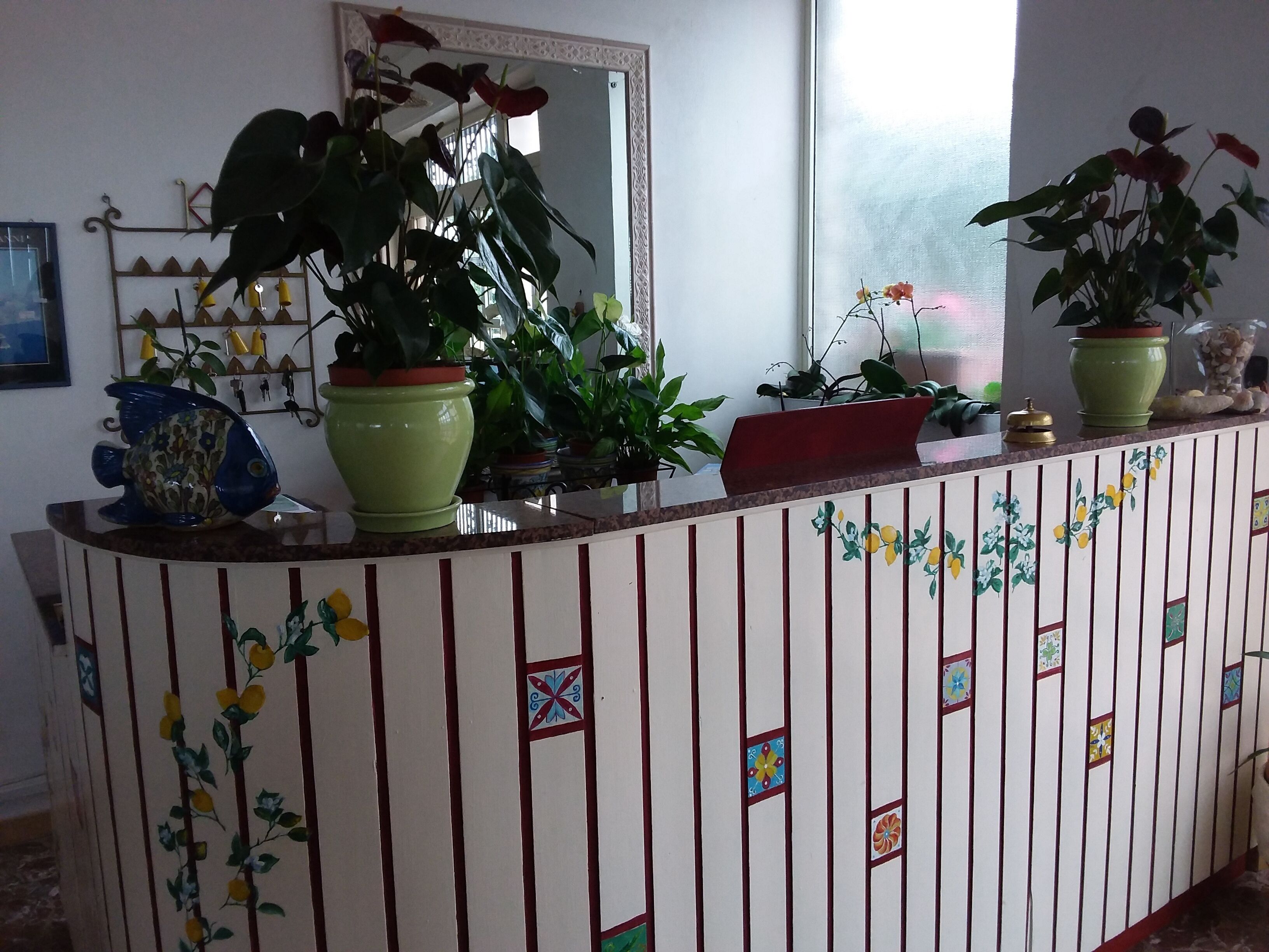 Una recepción con plantas, un espejo y un adorno mural.