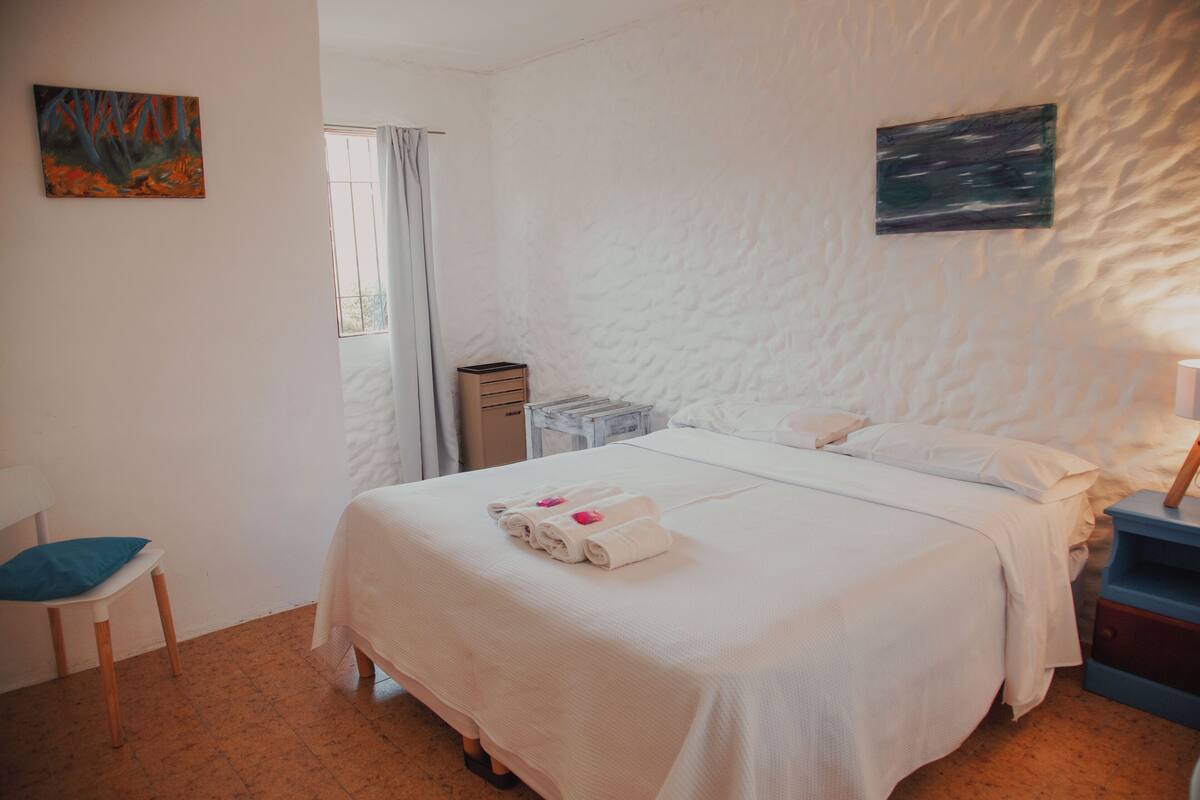 Une chambre d’hôtel avec un lit, une chaise, un bureau et une fenêtre.