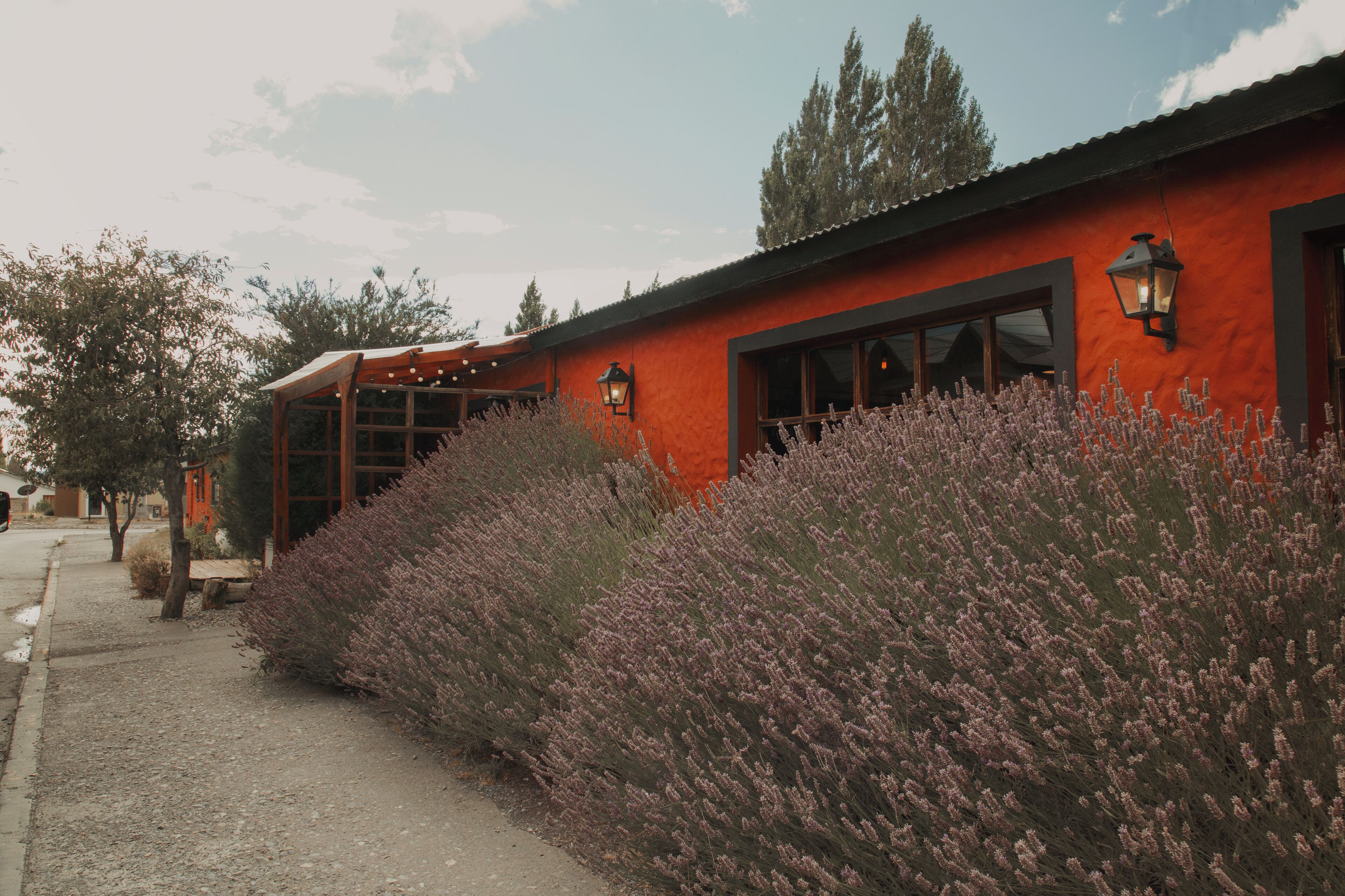 Un edificio con fachada roja, ventanas amplias y un sendero de grava.