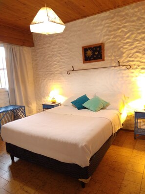 A bedroom with a bed, two bedside tables, a hanging lamp, and a wall-mounted picture. - Schilling Patagonia Travellers - Hostel (El Calafate)