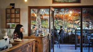 L’intérieur d’un restaurant est aménagé avec des meubles en bois, un comptoir et une fresque représentant une scène de forêt.