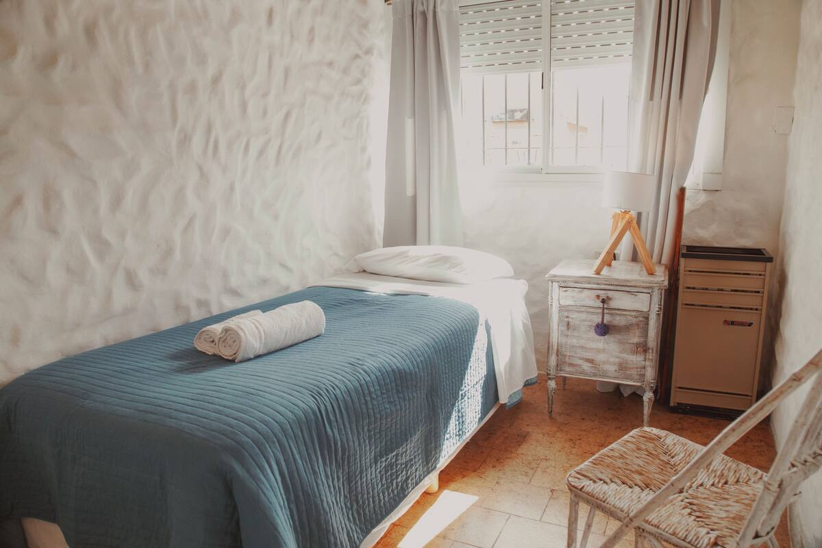 Une chambre à coucher comprenant un lit, une table de chevet, une chaise et une commode.