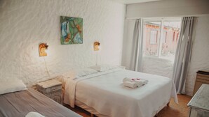 Une chambre d’hôtel avec deux lits, une table de chevet, un tableau au mur et une fenêtre avec des rideaux.
