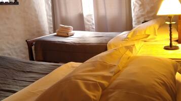 A hotel room with a bed, a bedside table, a lamp, and a window with curtains.