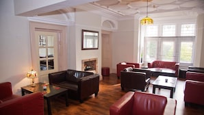 A spacious living room with leather sofas, a fireplace, and large windows. - Heath Cottage Hotel (Dewsbury)