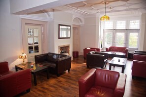 A spacious living room with leather sofas, a fireplace, and large windows.