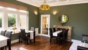 A dining area with a fireplace, a mirror, and a view through a glass door. - Heath Cottage Hotel (Dewsbury)