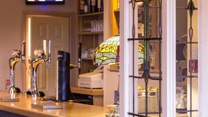 A bar area with multiple taps, a black coffee machine, and a stained glass window. - Heath Cottage Hotel (Dewsbury)