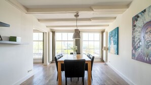 A dining area with a wooden table, black chairs, and a hanging pendant light. - Amsterdam Centre Harbour Apartments (Amsterdam)
