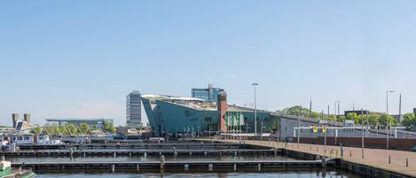 A waterfront area with a modern building, a bridge, and a marina.