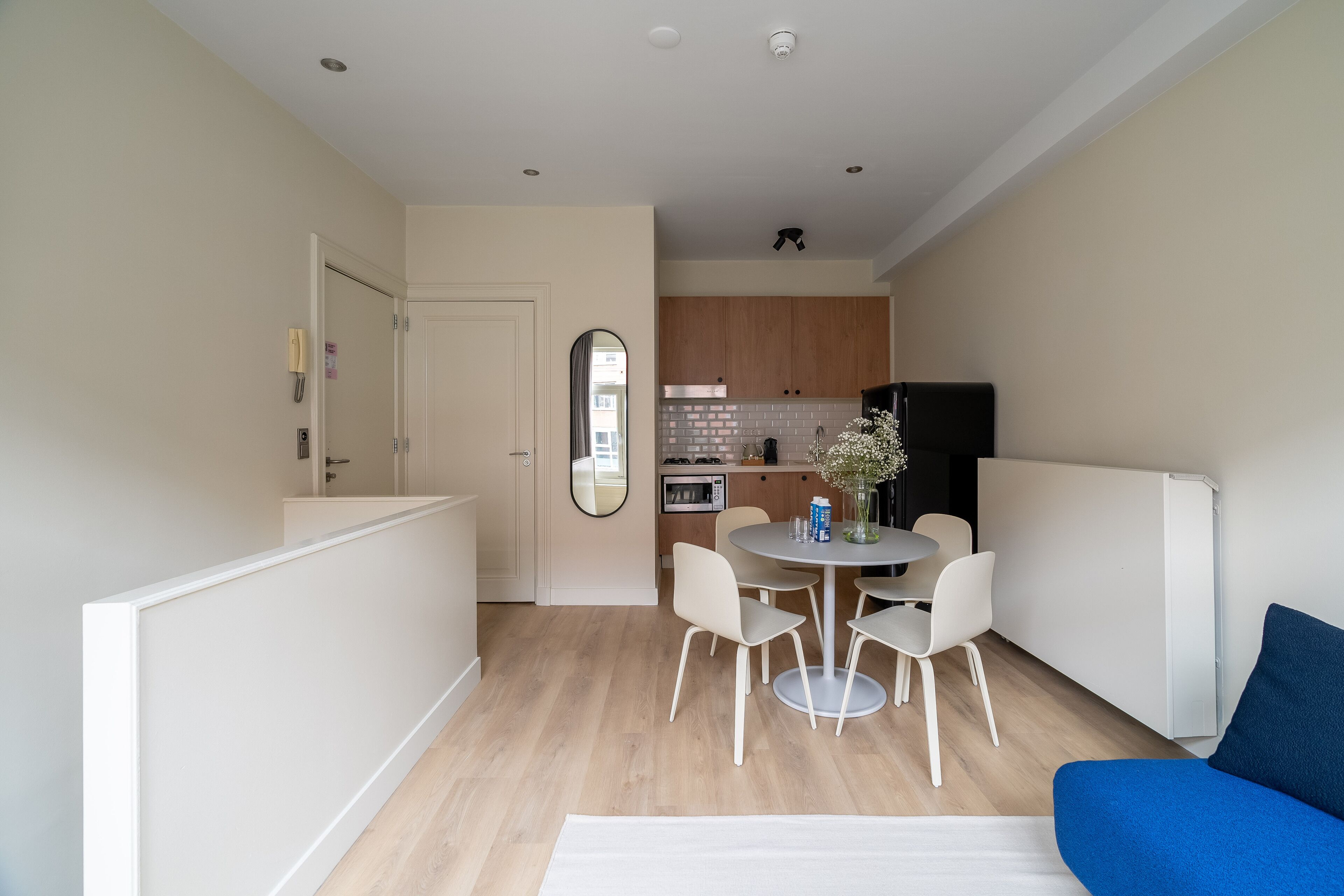 Una cucina moderna con mobili in legno, un frigorifero nero e un'area pranzo con un tavolo rotondo e quattro sedie.