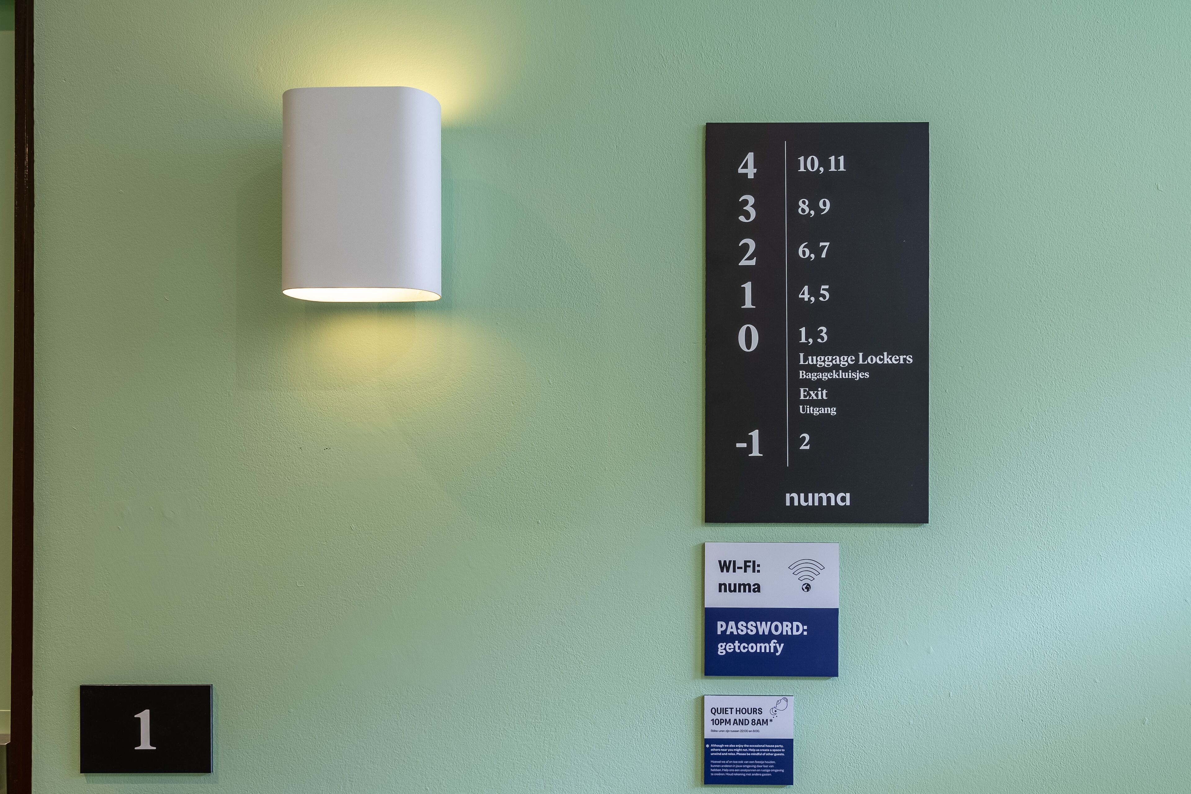 A wall with a number sign, a lamp, and signs indicating Wi-Fi, password, and quiet hours.