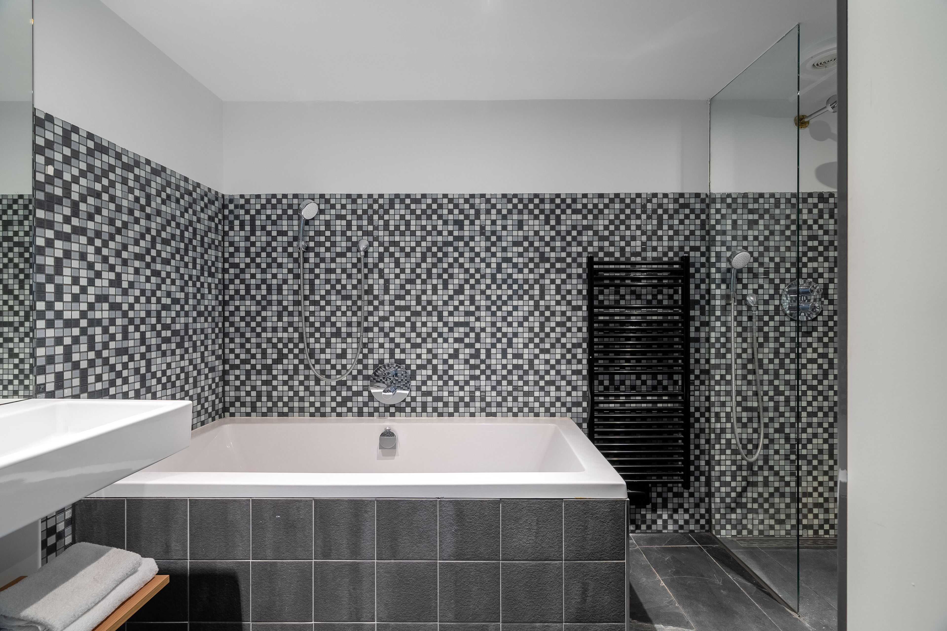 A modern bathroom with a large bathtub, a shower area, and a tiled wall.