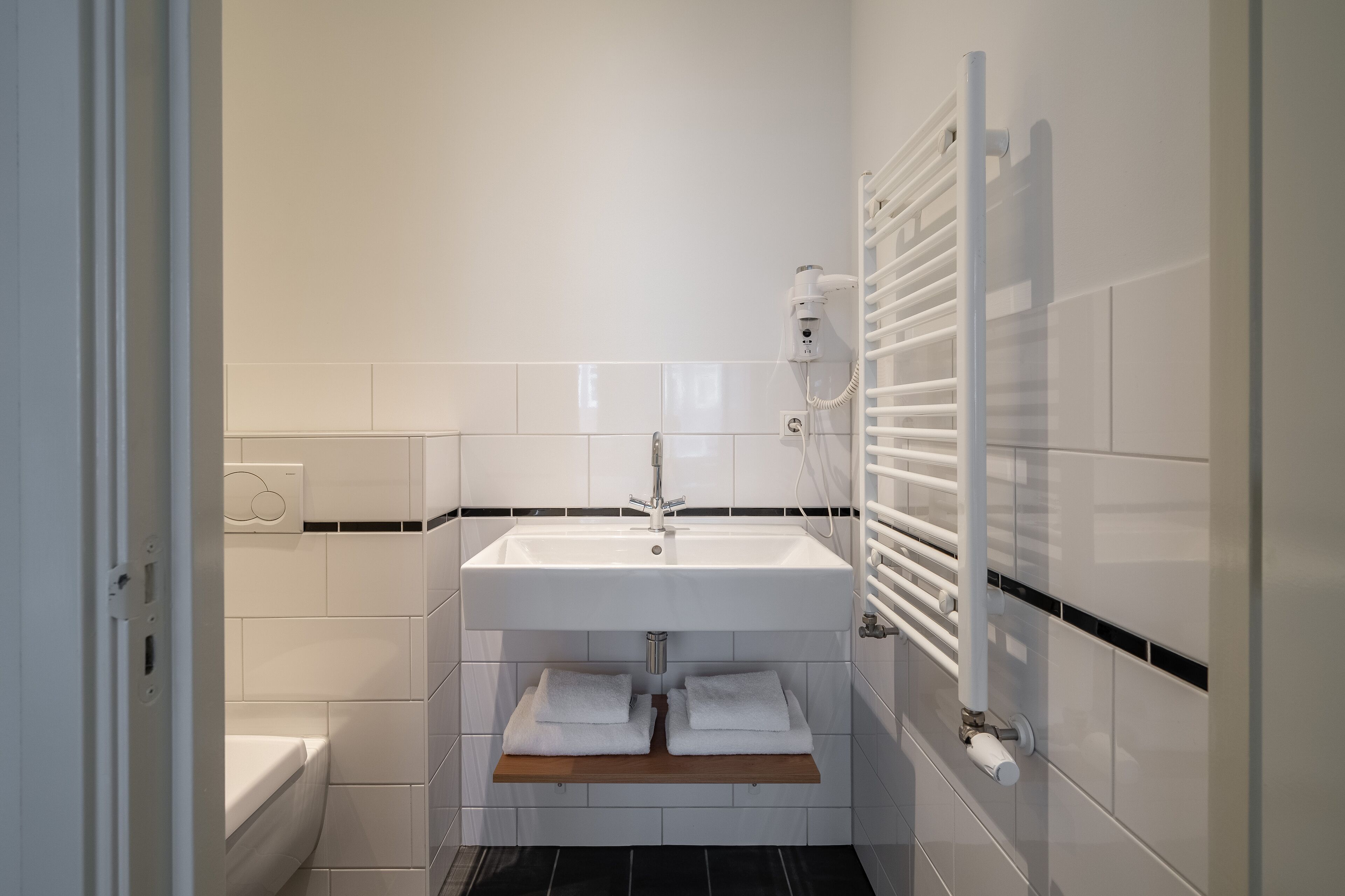 Une salle de bain moderne avec un lavabo blanc, un porte-serviettes et un radiateur encastré.