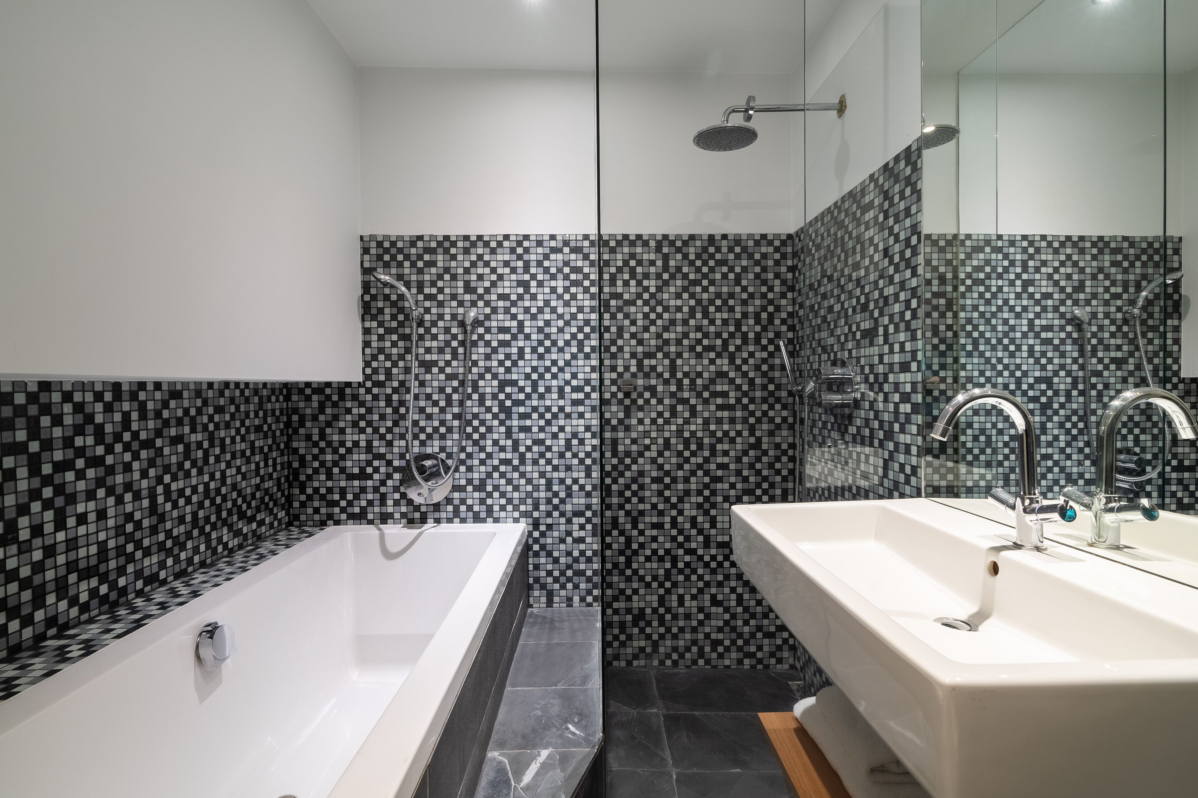 A modern bathroom with a large bathtub, a separate shower area, and a vanity with a sink.