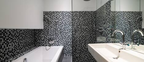 A modern bathroom with a large bathtub, a separate shower area, and a vanity with a sink.