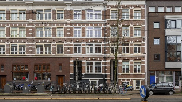 Een rij herenhuisen van baksteen met gelijkmatige raamrozetten en een centrale ingang.