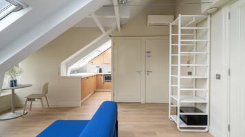 Een moderne loft slaapkamer met dakraam, een inbouw bureau en een witte kastenwand.