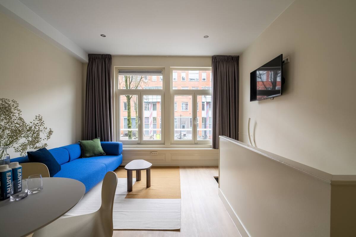 A modern living room with a blue sofa, a small table, and a TV mounted on the wall.