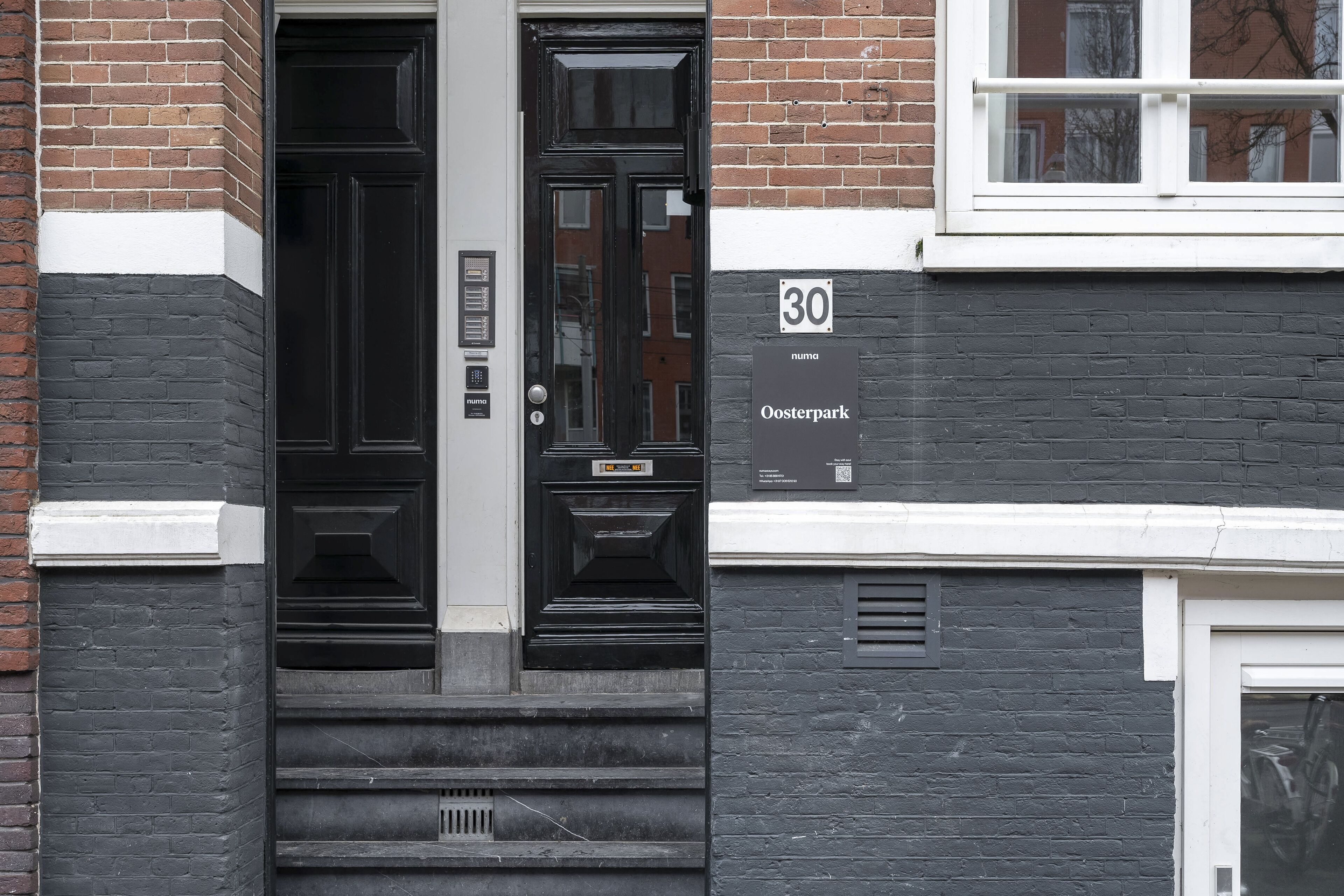 A black door with a number plate, a staircase, and a sign indicating the address as 30 Oosterpark.