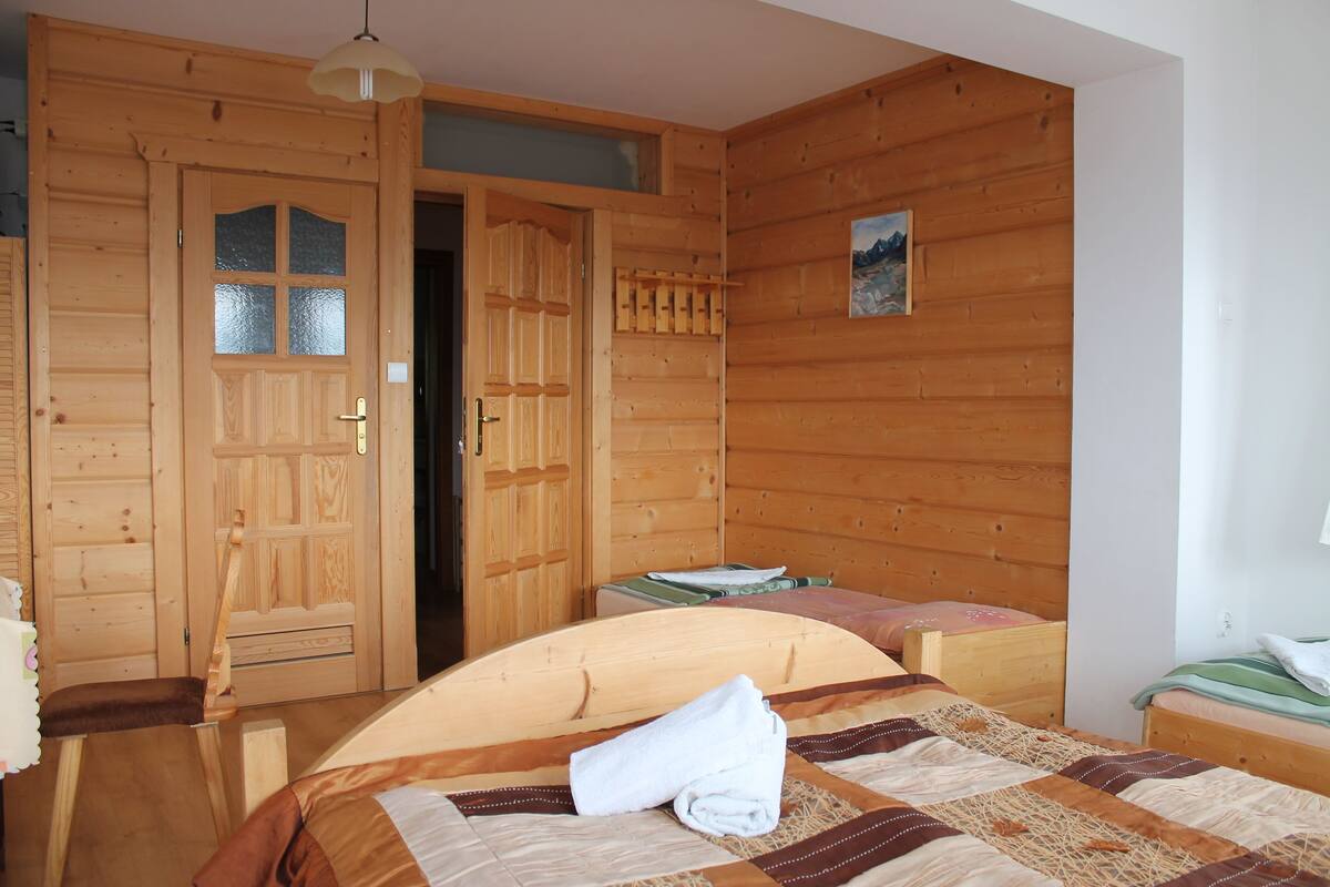 Une pièce de cabane en bois comprenant un lit, une petite table et une porte.
