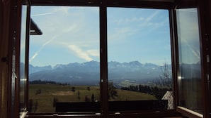 Une pièce dotée d’une grande fenêtre donnant sur des montagnes enneigées et un ciel dégagé.