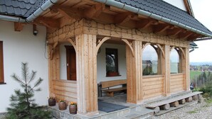 Une cabane en bois avec une véranda, des marches en pierre et un banc.