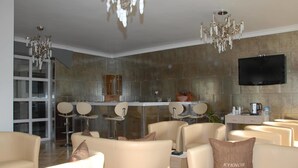 Ein modernes Wohnzimmer mit beigen Sofas, einer Kristallleuchtre und einem an einer strukturierten Wand montierten Flachbildfernseher.