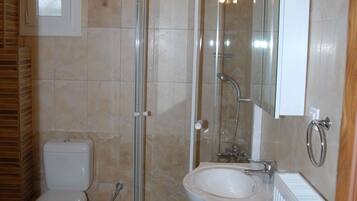 Un baño con ducha de vidrio, inodoro, lavabo y espejo.