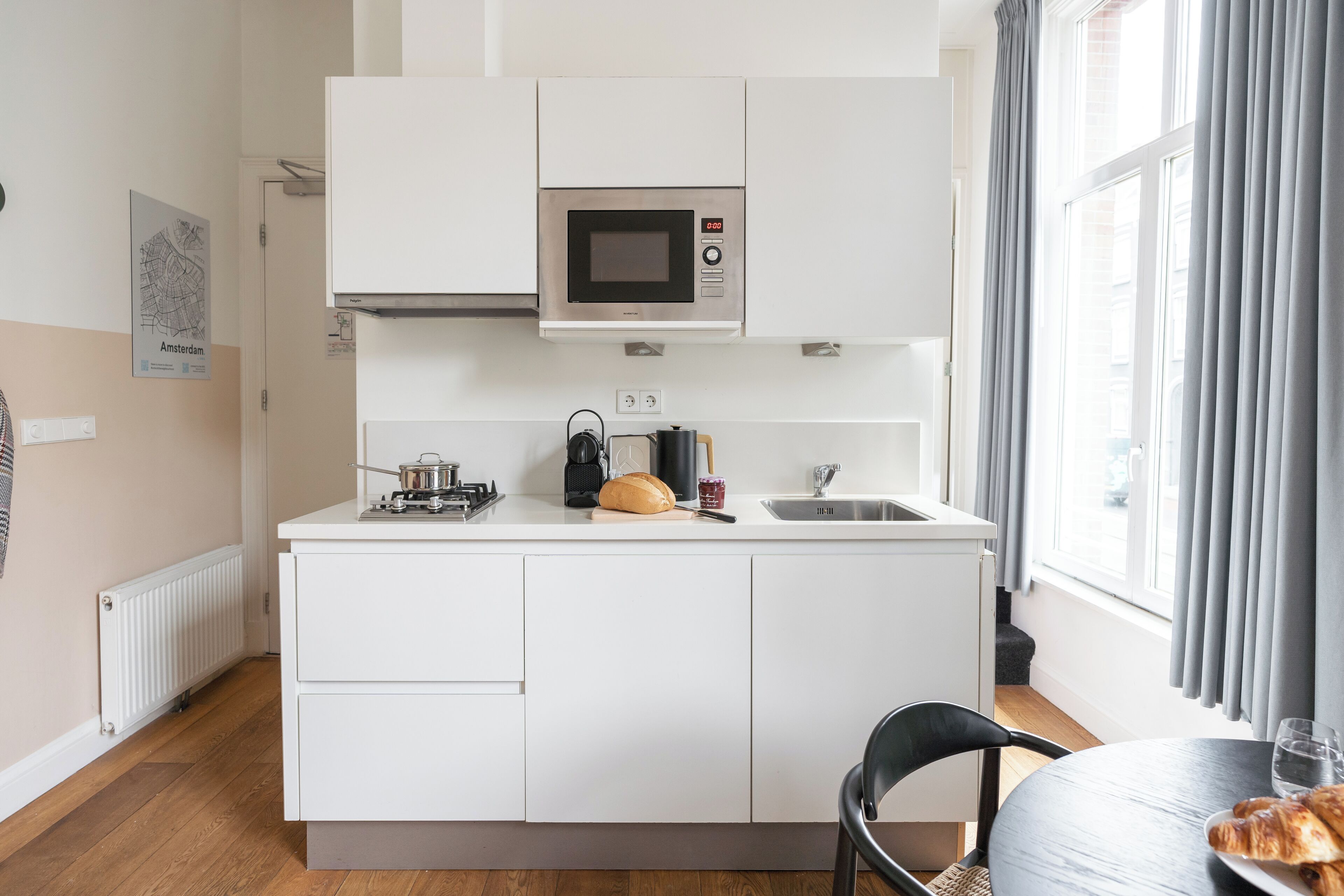 A compact kitchen with a microwave, sink, and a small dining area with a chair and table.