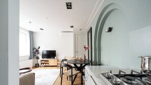 A modern kitchen with a gas stove, a dining area with a round table and chairs, and a TV in the background. -  Numa Amsterdam Helmers (Amsterdam)