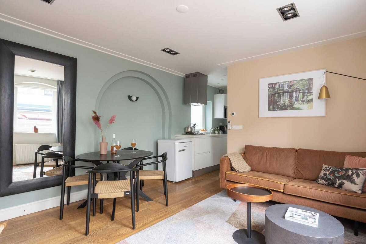 A modern living room with a brown sofa, a round coffee table, and a dining area with a table and chairs.