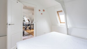 A bedroom with a large bed, a skylight, and a view of a dining area. -  Numa Amsterdam Helmers (Amsterdam)