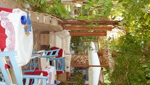 A courtyard with outdoor seating, stone flooring, and various plants. - Hôtel Sant'Andrea, The Originals Relais (Relais du Silence) (Marciana)