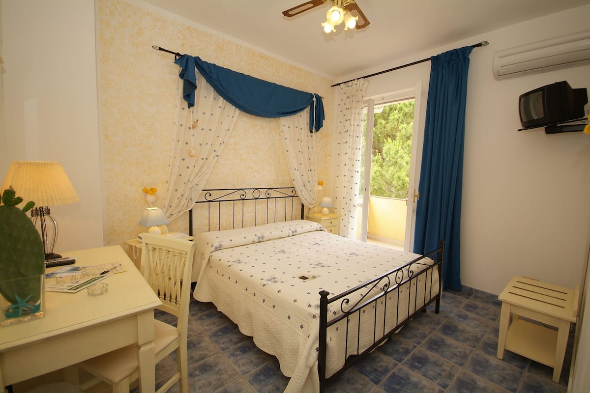 A bedroom with a bed, bedside tables, a desk, and a chair.