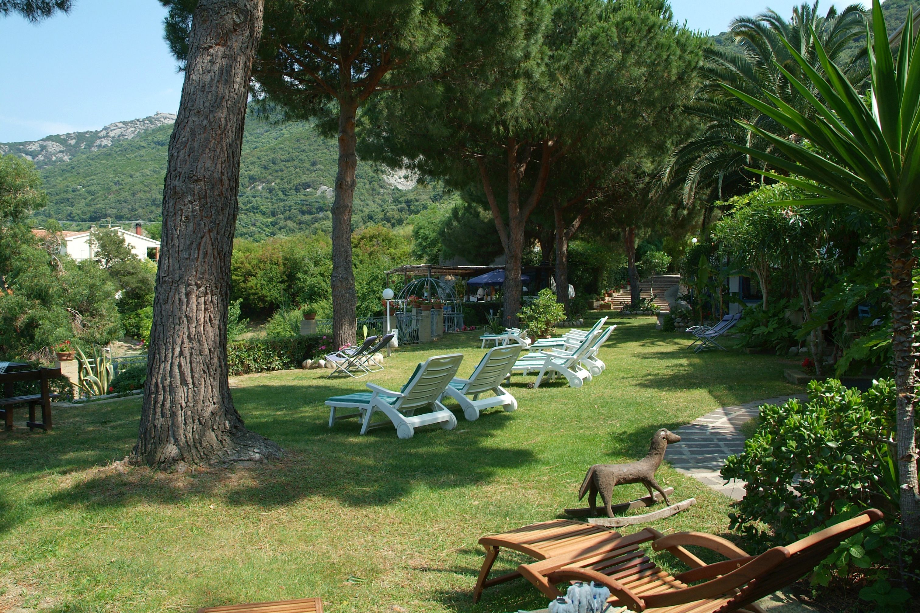 A garden with sun loungers, a wooden table, and a statue.
