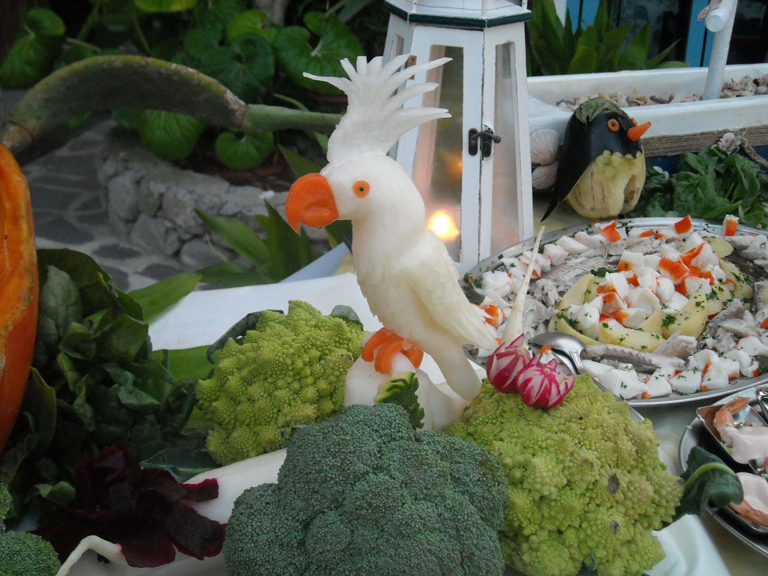 A table with various vegetables and a bird figurine.