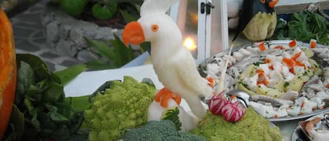 A table with various vegetables and a bird figurine.