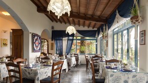 A restaurant with multiple tables, wooden chairs, and blue and white patterned tablecloths. - Hôtel Sant'Andrea, The Originals Relais (Relais du Silence) (Marciana)