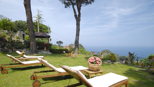 A sunny outdoor area with wooden lounge chairs and a wicker basket with flowers. - Hôtel Sant'Andrea, The Originals Relais (Relais du Silence) (Marciana)