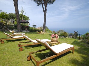 A sunny outdoor area with wooden lounge chairs and a wicker basket with flowers. - Hôtel Sant'Andrea, The Originals Relais (Relais du Silence) (Marciana)