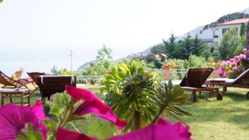 Ein Garten mit Liegestühlen und Meerblick.